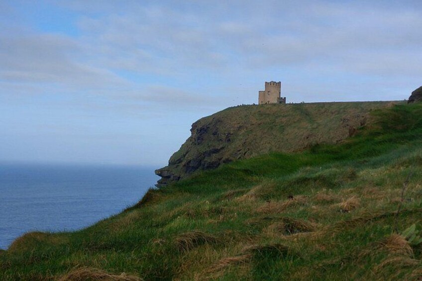 A coastal landscape with a castle on a grassy hill overlooking the sea. 3