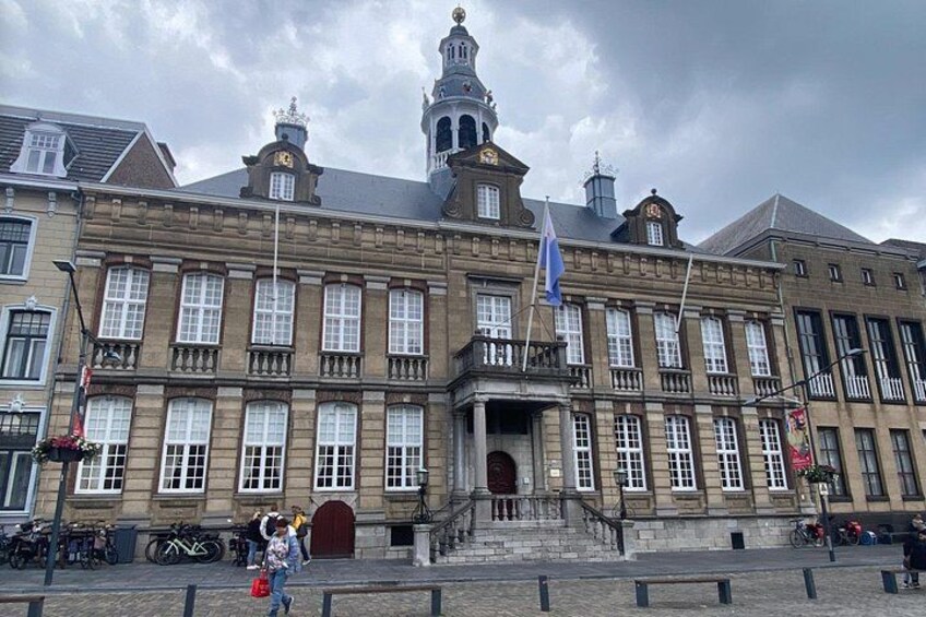 A historic building with a prominent clock tower, large windows, and a flag. 3