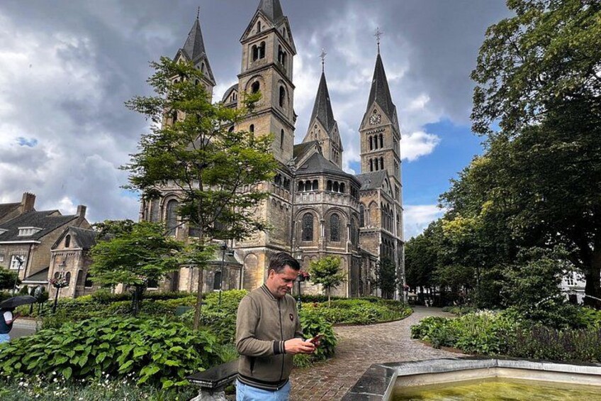 A historic church with twin spires, a person standing in a garden, and a pathway leading to the building. 2
