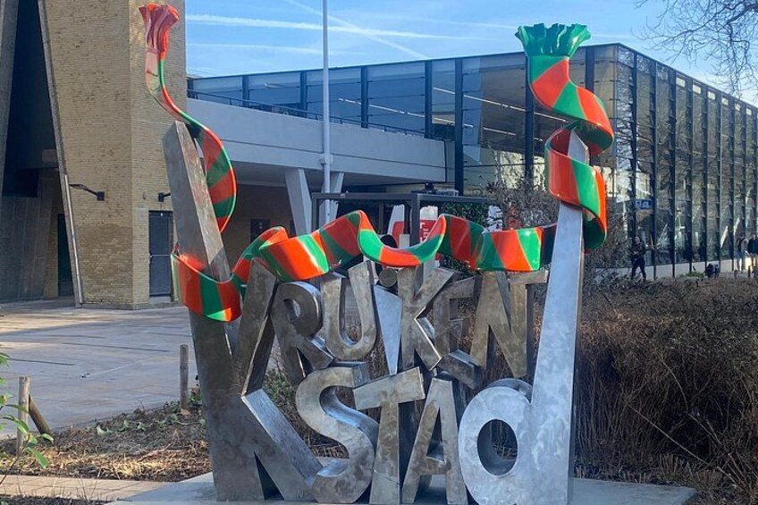 A metal sculpture with the text 'RUHN STAFO' and colorful ribbons. 2