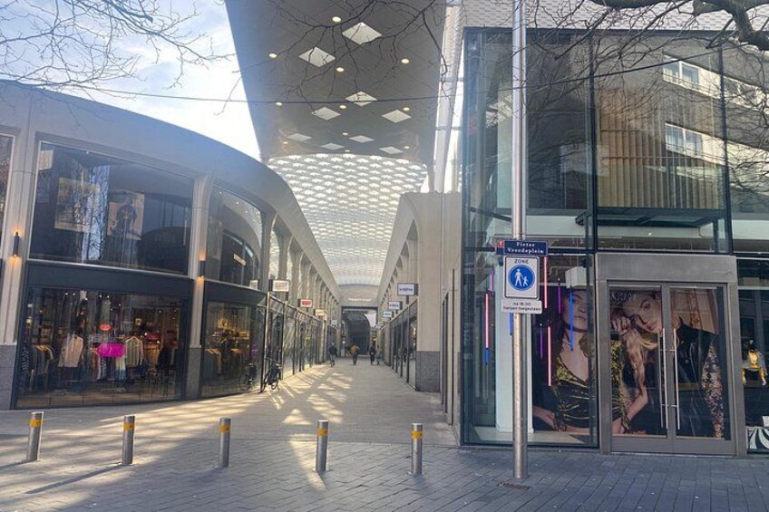 A modern shopping area with glass storefronts and a covered walkway. 4