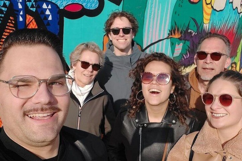 A group of people posing in front of a colorful mural. 2