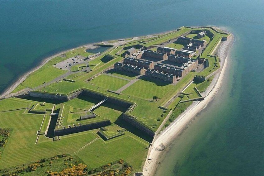 Vue aérienne d’une île fortifiée, avec un château central, entourée d’eau et de champs verdoyants. 5