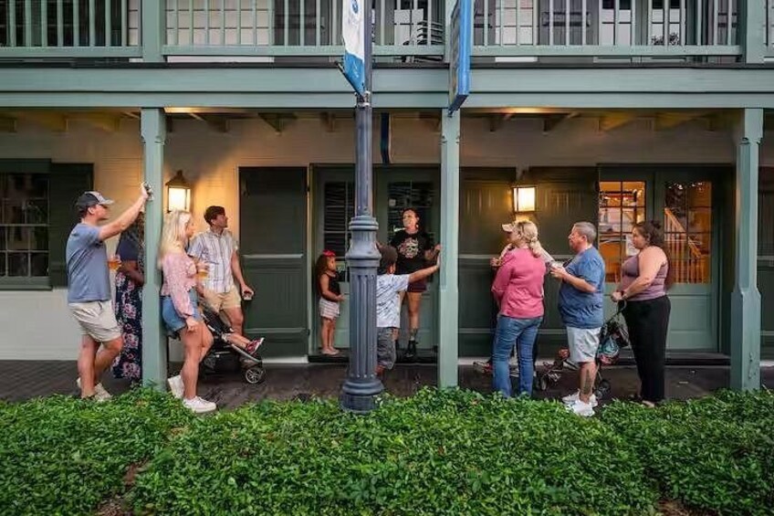 A group of people standing on a porch with a building in the background. 2