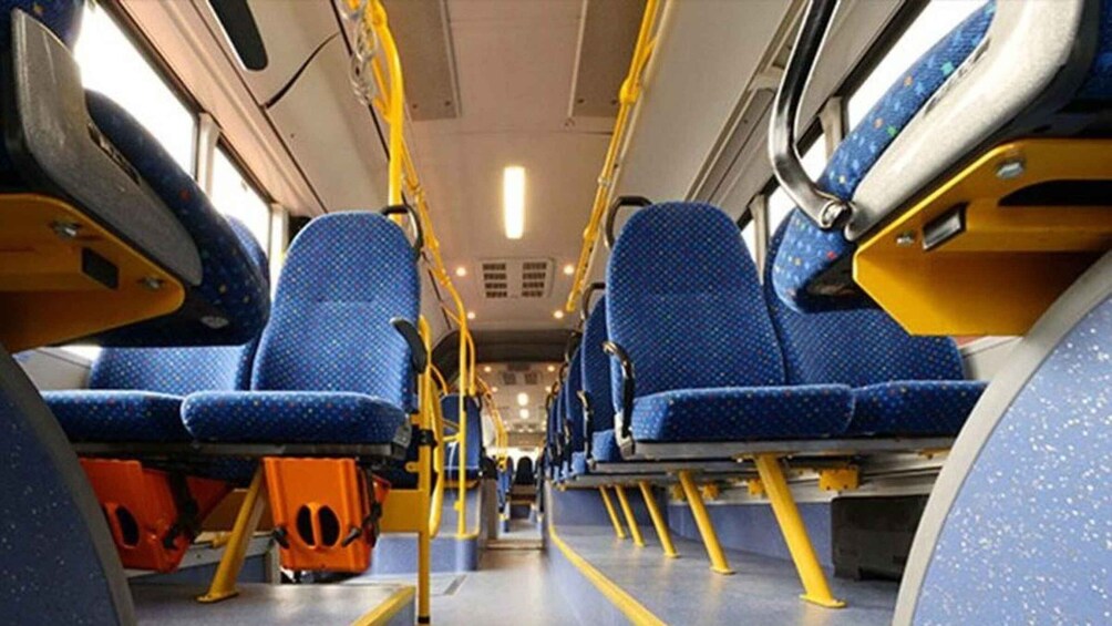 The interior of a bus with blue seats and yellow poles. 3