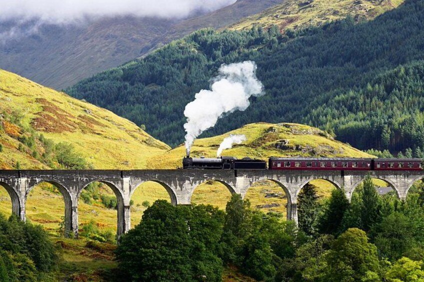 A steam train crossing a stone viaduct over a valley. 2