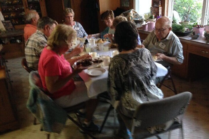 A group of people dining at a table in a room with wooden furniture and plants. 2