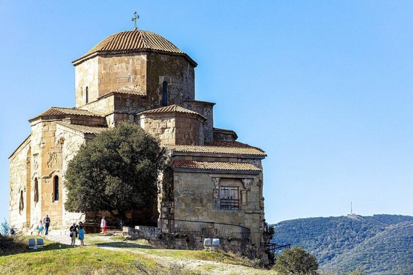 Una iglesia histórica con un campanario, rodeada por un paisaje montañoso. 5