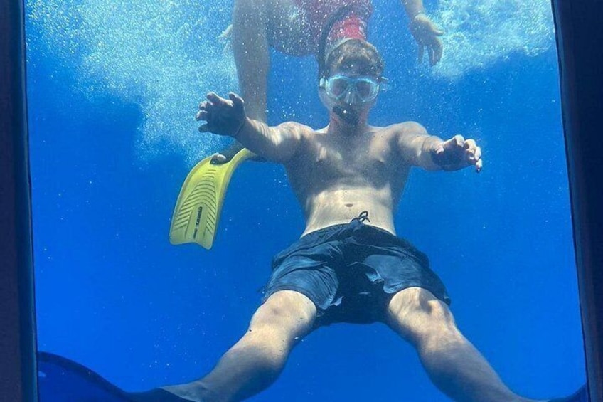 Una persona sott'acqua con una pinna gialla, indossa pantaloncini scuri e un boccaglio. 1