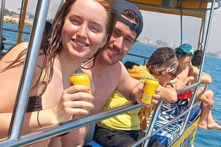 Persone su una barca, che sorseggiano bevande, con l'acqua e una costa lontana sullo sfondo. 1