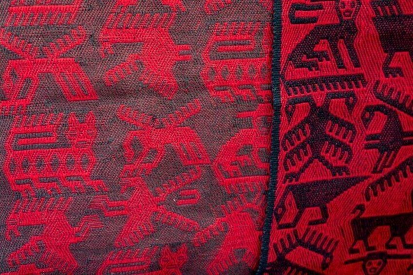 Stof med røde og sorte mønstre, muligvis et traditionelt eller kulturelt design. 2