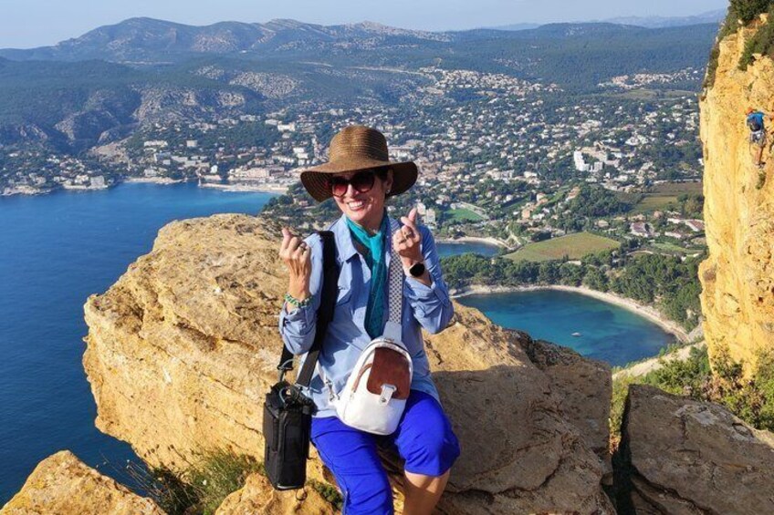 A person sitting on a cliff overlooking a coastal town with a view of the sea and mountains. 4
