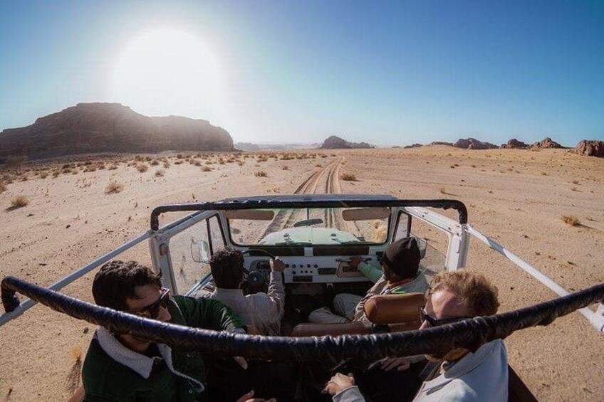 A vehicle on a desert road with a clear sky and distant mountains. 3