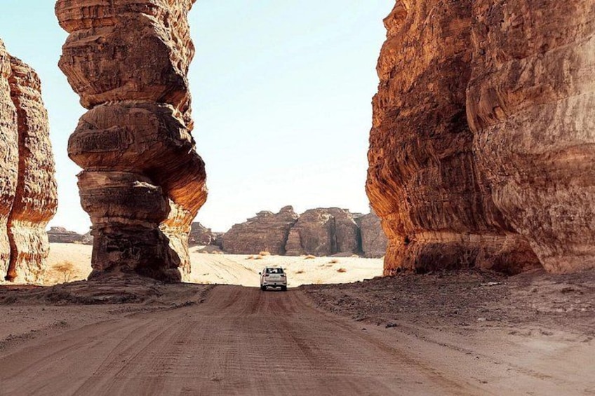 A vehicle on a dirt road between rock formations. 4