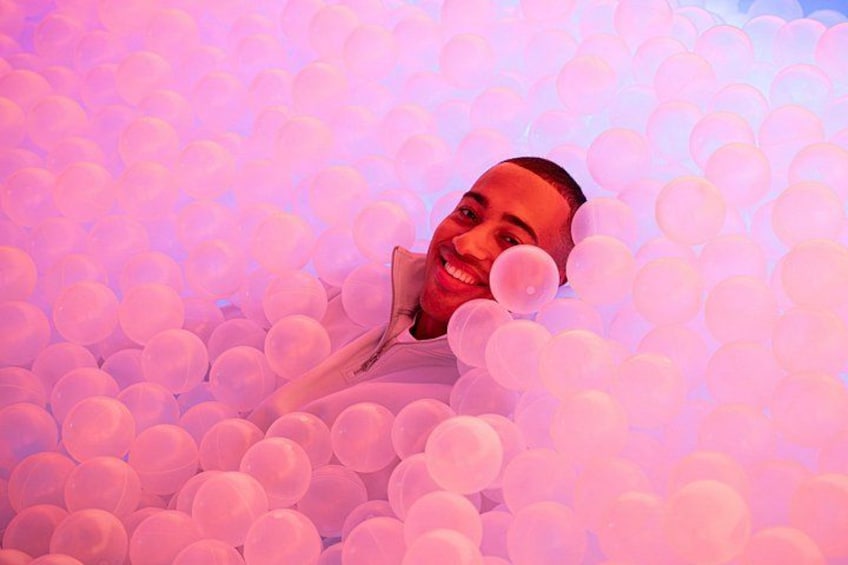 Una persona rodeada de numerosos globos blancos. 4