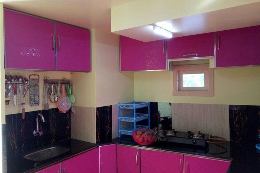 A kitchen with pink cabinets, a black countertop, and a window above the sink. 2