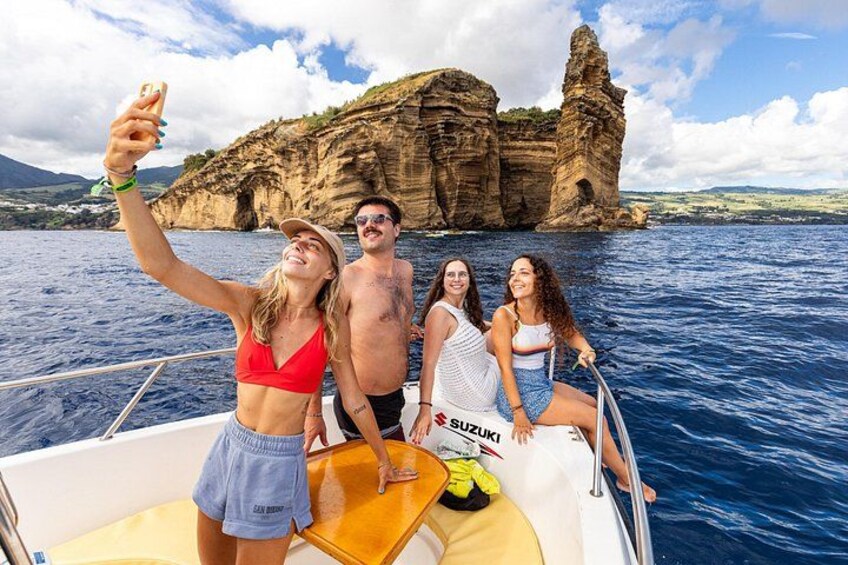 A group of people on a boat with a rocky cliff in the background. 2