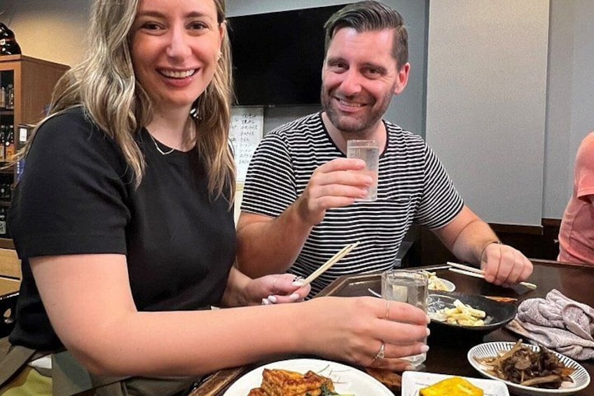 Two people dining at a restaurant with plates of food and chopsticks. 3