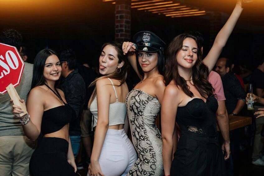 A group of people at a social event, some holding drinks and one holding a stop sign. 5
