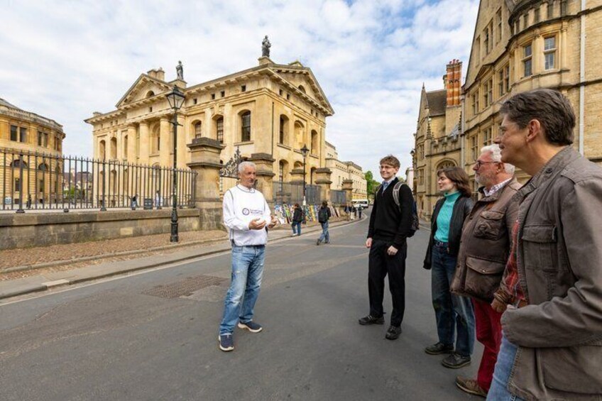 A group of people standing on a street in front of a historic building with classical architecture. 3