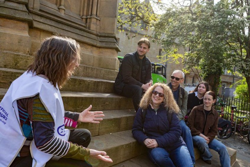 A group of people sitting on steps outdoors, engaged in conversation. 5