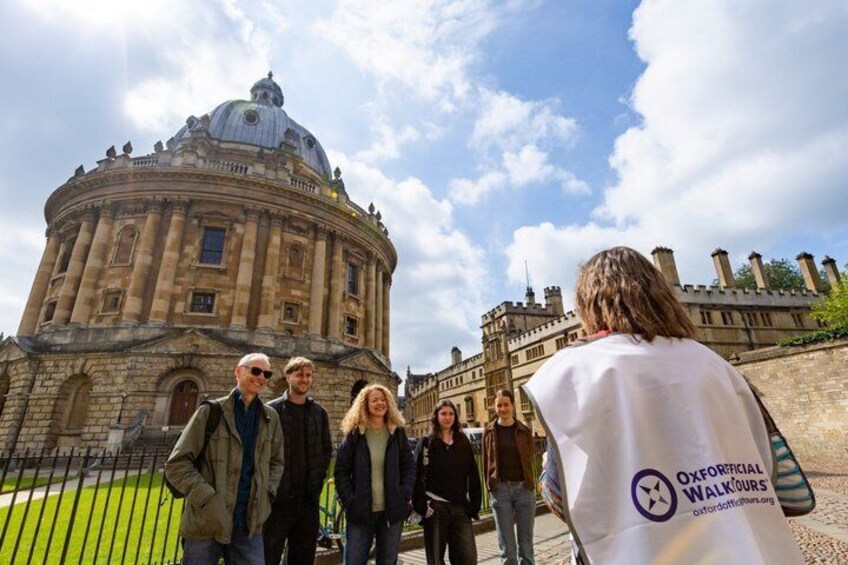 A group of people standing in front of a historic building with a dome and a clock tower. 1