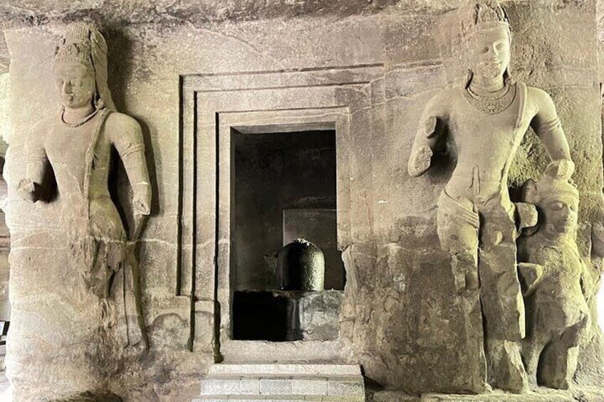 A stone carving of two figures with a doorway in the background. 2