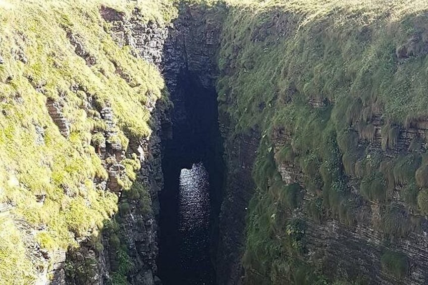 Eine tiefe Schlucht mit steilen, felsigen Klippen und einem schmalen Wasserlauf. 4