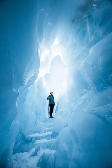 A person standing in a narrow, icy passageway with a bright light at the end. 5