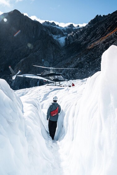 A person walking towards a helicopter in a snowy mountainous area. 3