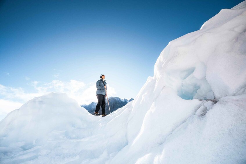 A person standing on a snow-covered mountain peak with a clear sky. 1