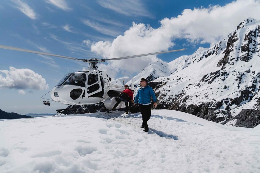 A helicopter on a snowy mountain with people walking nearby. 4
