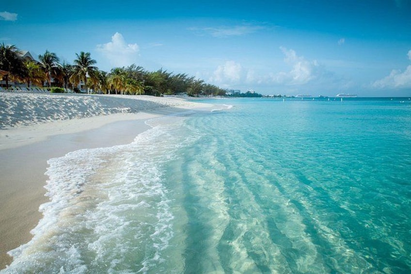 Een strand met helder turquoise water, wit zand en palmbomen. 2