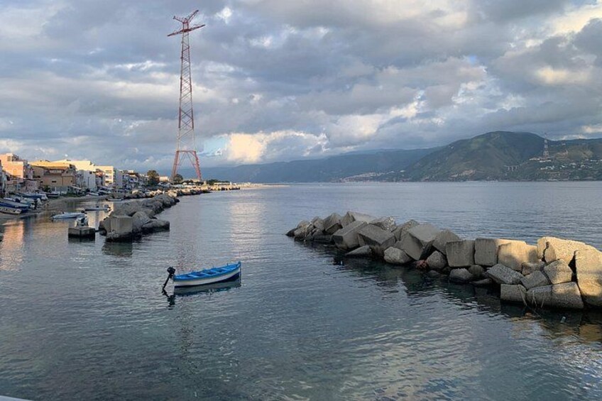 A coastal scene with a rocky breakwater, a small boat, and a distant power line tower. 3