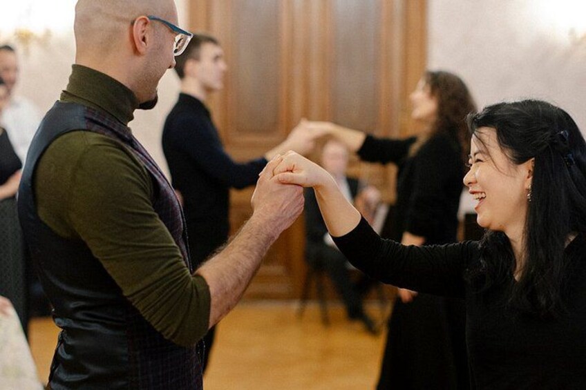 A man and a woman holding hands, possibly dancing, in a room with wooden paneling. 3