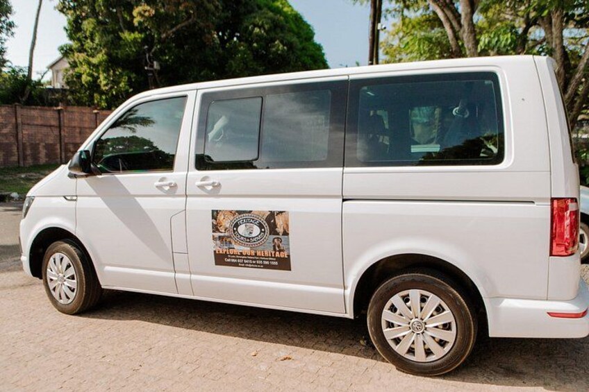 A white van parked on a paved surface with a logo on its side. 2