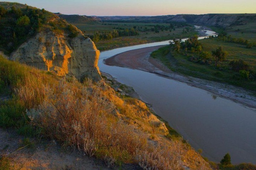 A river winding through a valley with a rocky outcrop on the left. 3