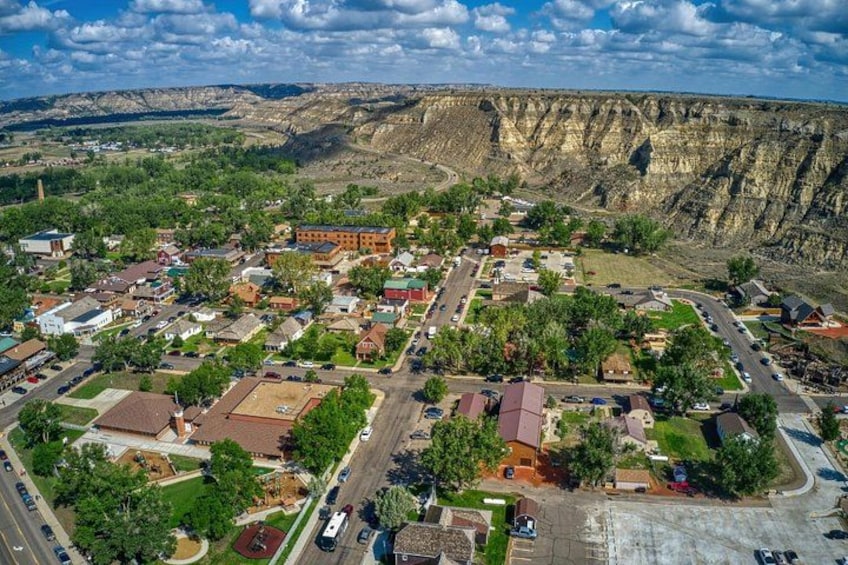 A town nestled in a valley with a prominent cliff face in the background. 4