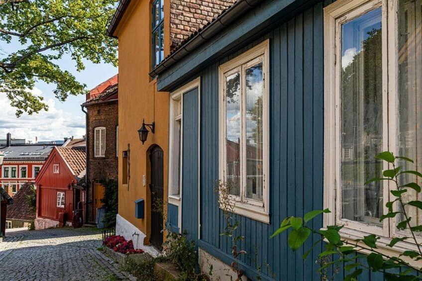 En kullerstensgata kantad av färgglada byggnader, ett blått hus med en vit dörr och en röd byggnad med ett rött tak. 4