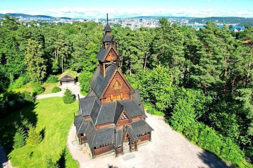 En trækirke med et stejlt tag og et kirketårn, omgivet af tæt skov. 1