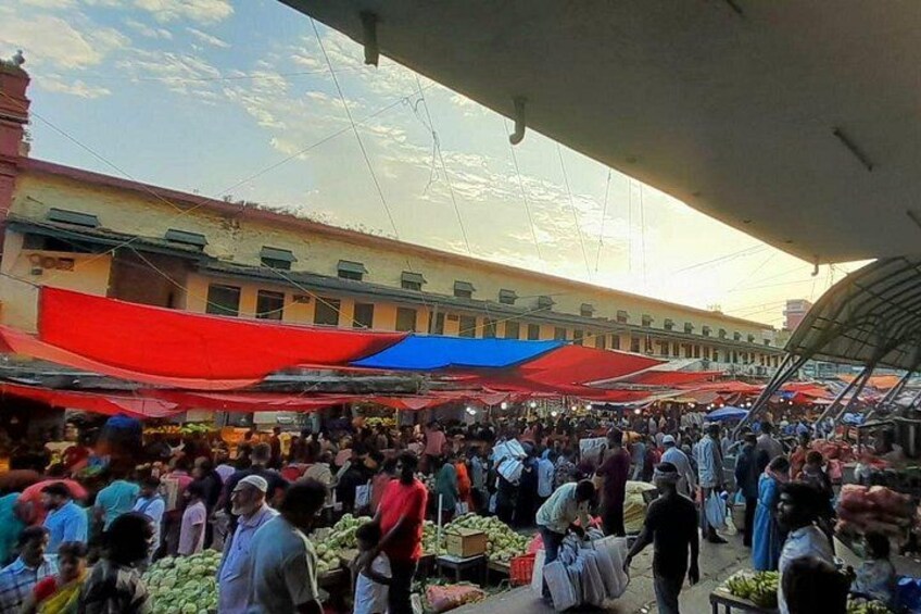 A crowded outdoor market with people shopping and vendors selling goods. 2