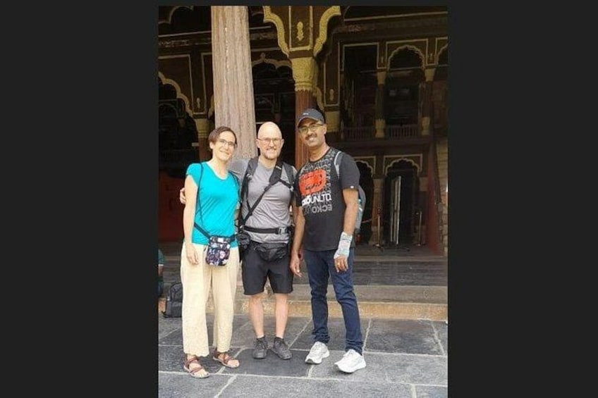 Trois personnes se tiennent devant un bâtiment à l’architecture richement décorée. 2