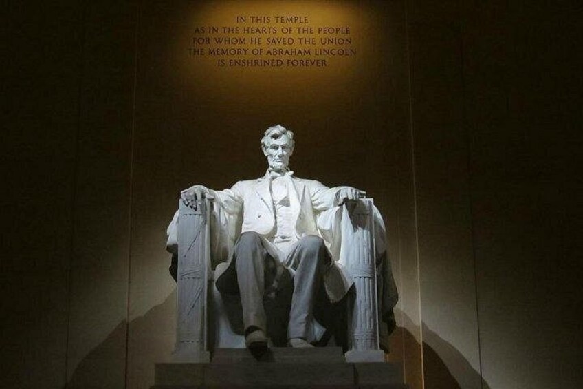 Una estatua de Abraham Lincoln sentado sobre un pedestal con una placa en la parte superior. 2