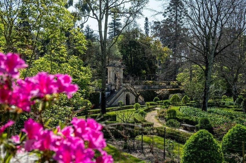 A garden with a stone bridge, manicured hedges, and flowering plants. 2