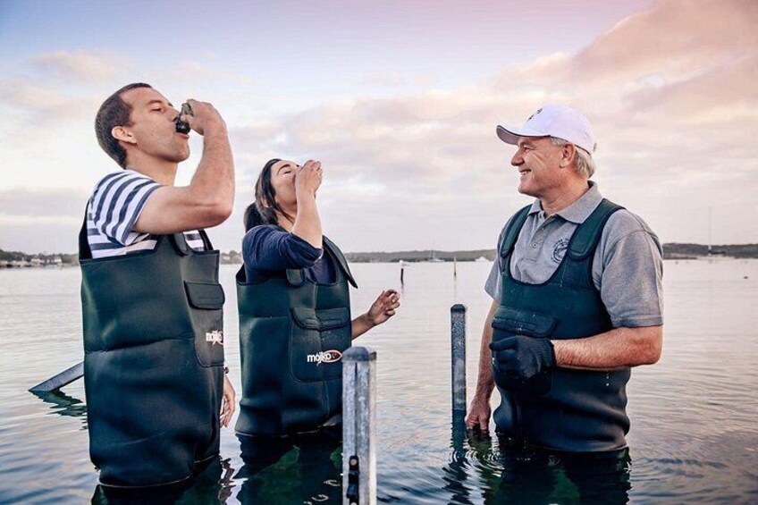 Three people in waders standing in water, one holding a camera. 4