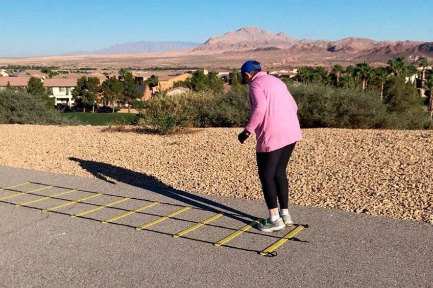 Una persona colocando una cuerda de saltar sobre una superficie pavimentada, con un paisaje desértico al fondo. 5