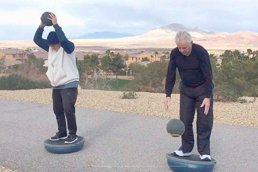 Dos personas sobre tablas de equilibrio al aire libre, con un paisaje montañoso de fondo. 2