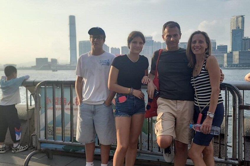 A group of people standing by a waterfront with a city skyline in the background. 4
