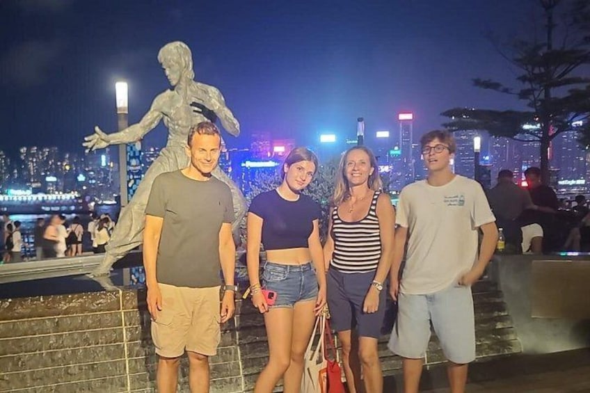 A group of people standing in front of a statue with a cityscape in the background. 3
