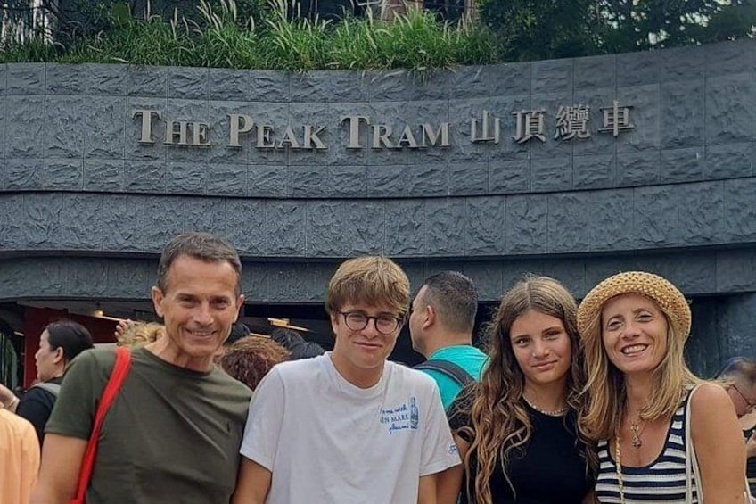 A group of people in front of a sign that reads 'The Peak Tram.' 2